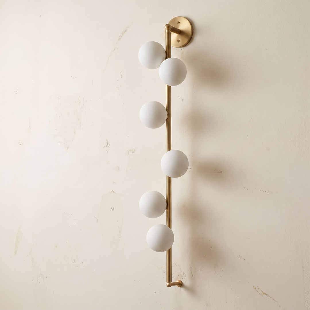 Wall-mounted light fixture with six white spherical lights on a beige wall.